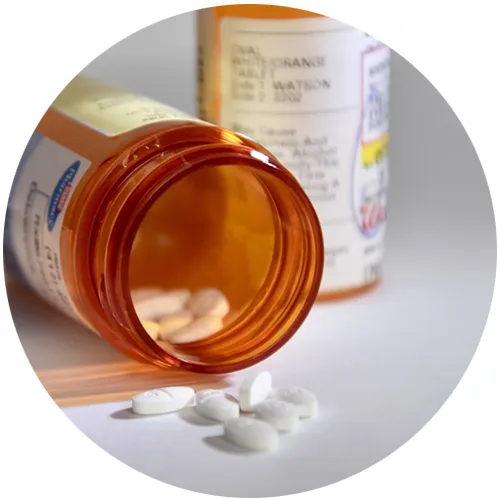 Prescription bottle tipped over with white tablets spilling out
