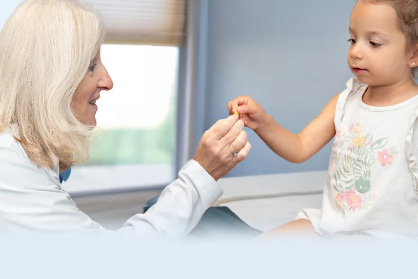 Allergist offering a small food sample to a young girl during a supervised food challenge