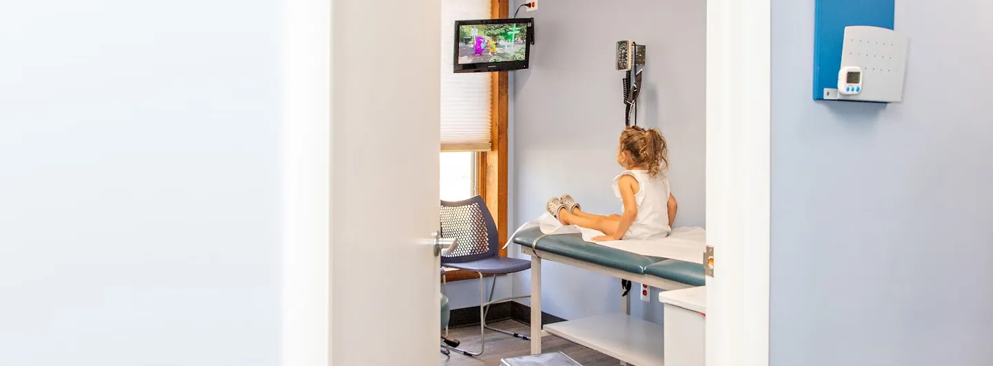 Child sitting on the exam table in an exam room